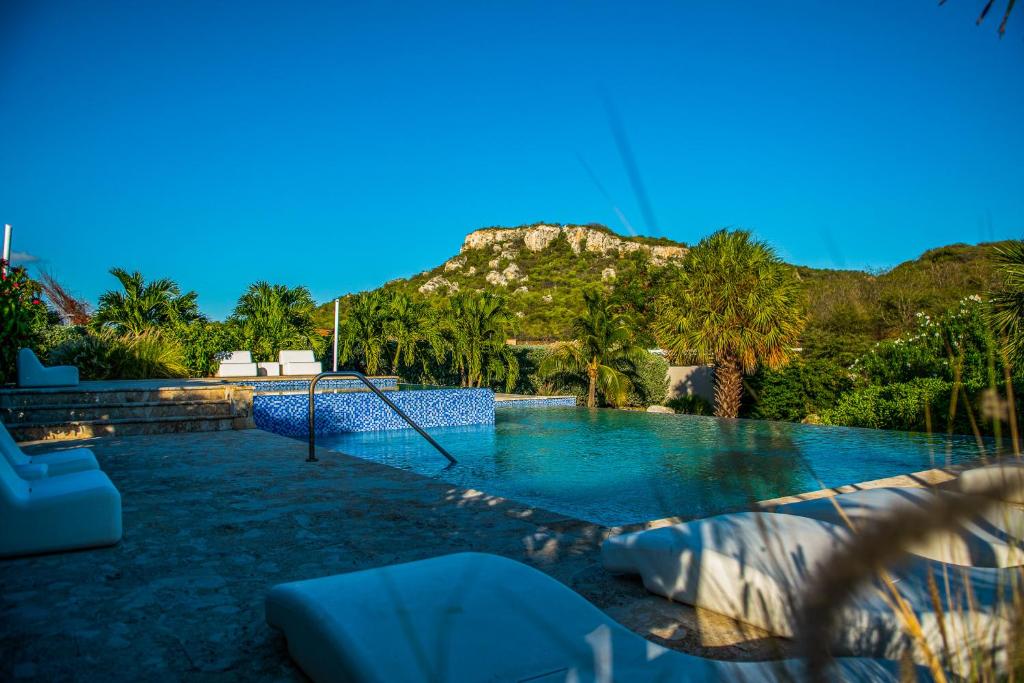 uma piscina com um baloiço e uma montanha ao fundo em Blue Bay Resort luxury apartment Green View em Dorp Sint Michiel