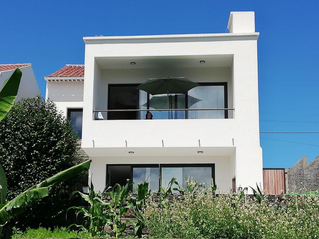 een wit huis met een parasol op het balkon bij Casa da Boa Vista in Algarvia
