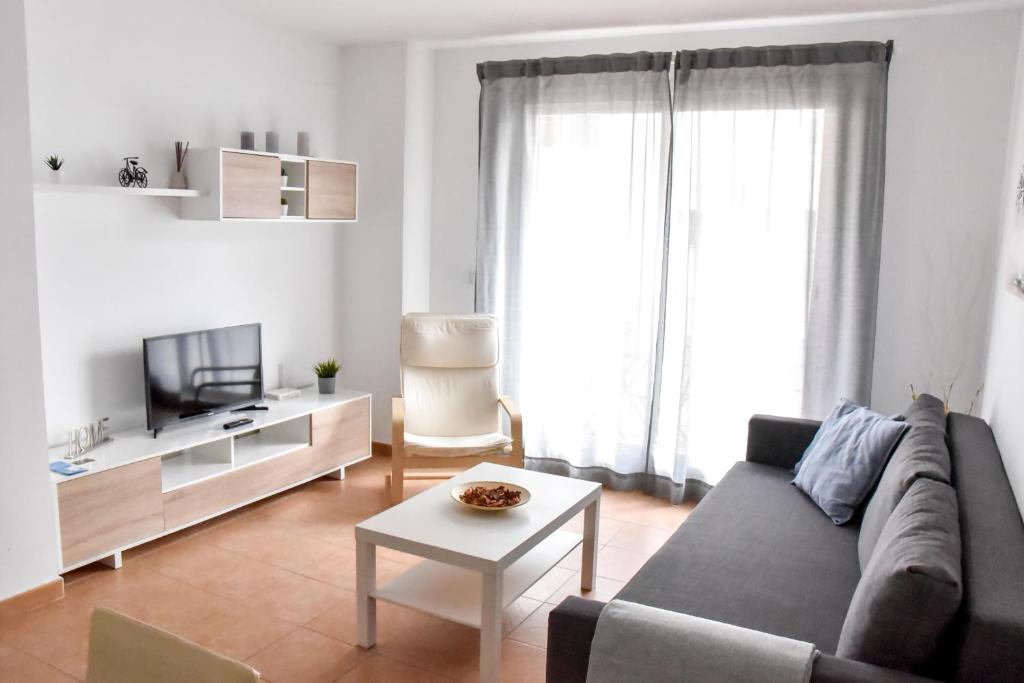 uma sala de estar com um sofá, uma televisão e uma mesa em Amplio con Parking, Club y Piscina junto a Sevilla em La Algaba