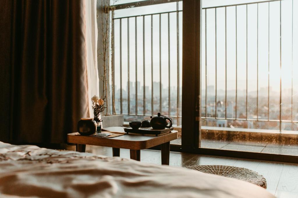 um quarto com uma cama e uma mesa em frente a uma janela em Apastar Luxury - Vinhomes Smart City em Hanói