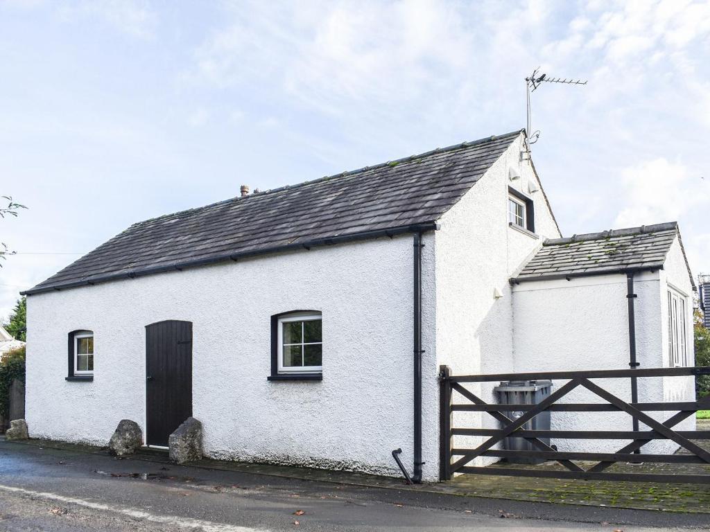 Gleaston的住宿－Guards Cottage，一座白色的小建筑,有黑色的屋顶