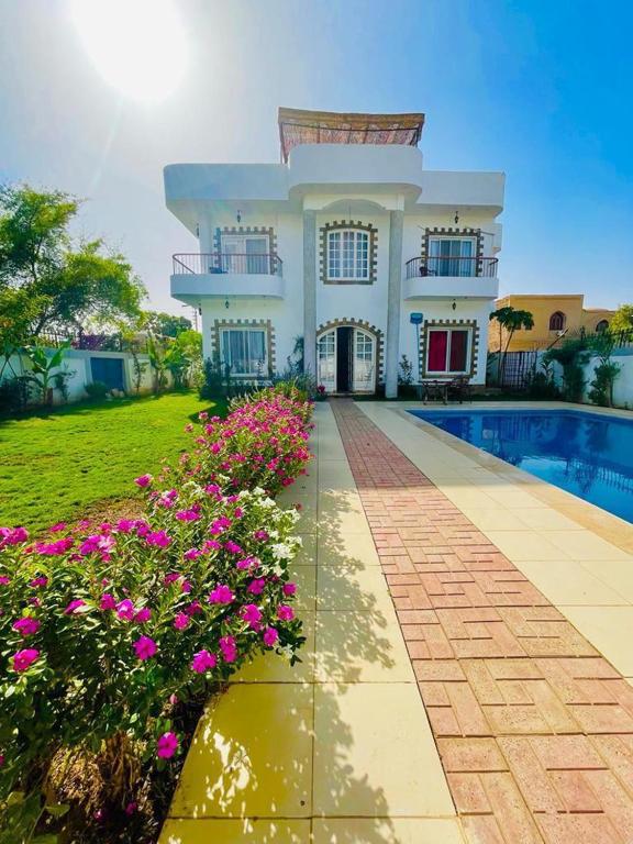a house with a swimming pool and flowers at Ali Luxury Villa in Luxor