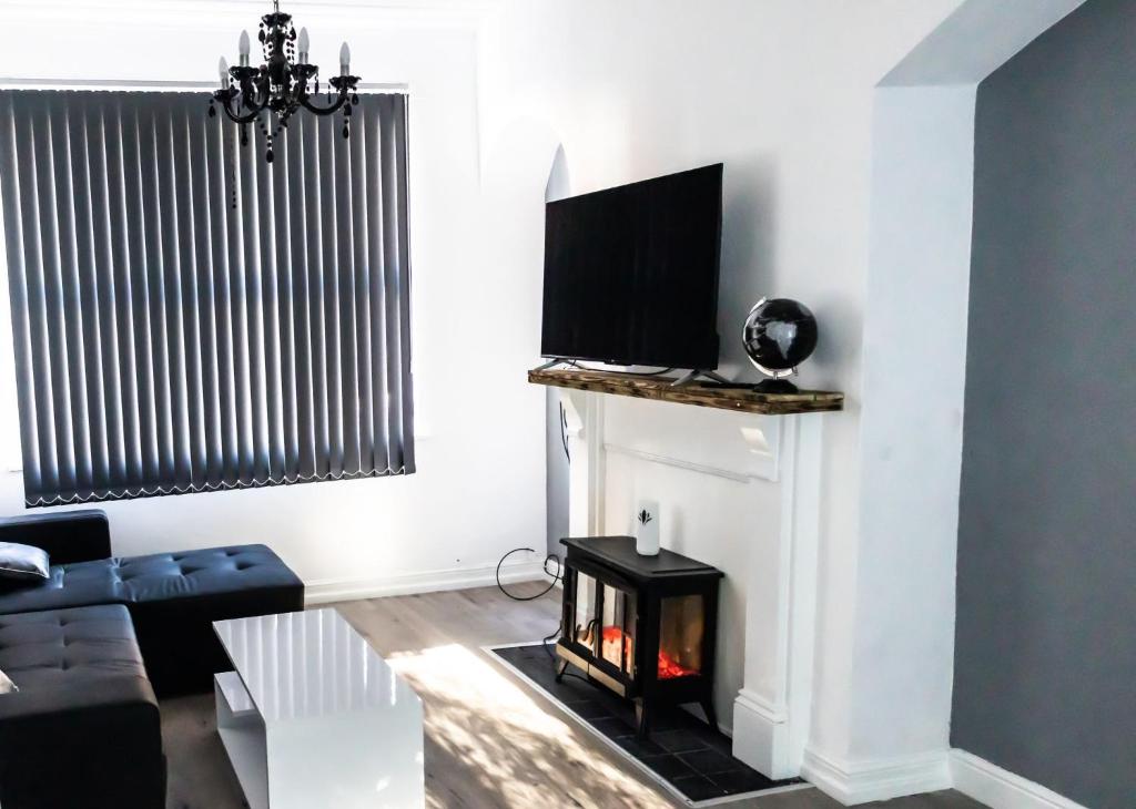 uma sala de estar com lareira e televisão em Cozyhouses em Hull