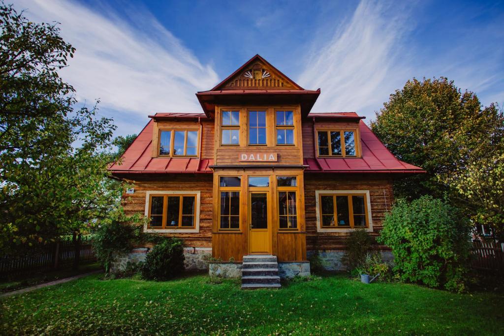 een houten huis met een rood dak bij Willa Dalia in Rabka