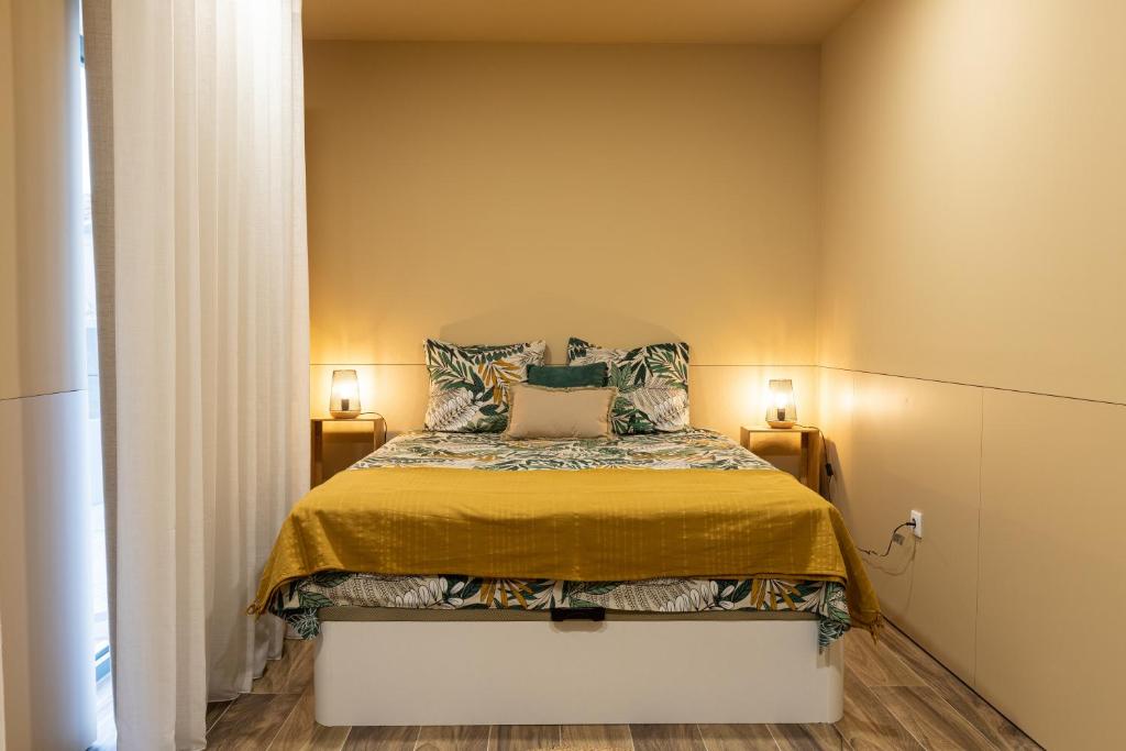 a bedroom with a bed with two lamps on either side at Dorigem Rooms in Casal de Loivos