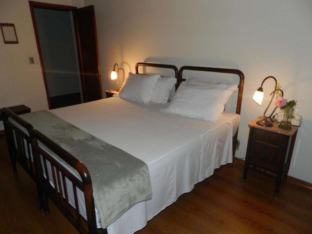 a bedroom with a large bed with white sheets and pillows at Hotel Bragança in Caxambu