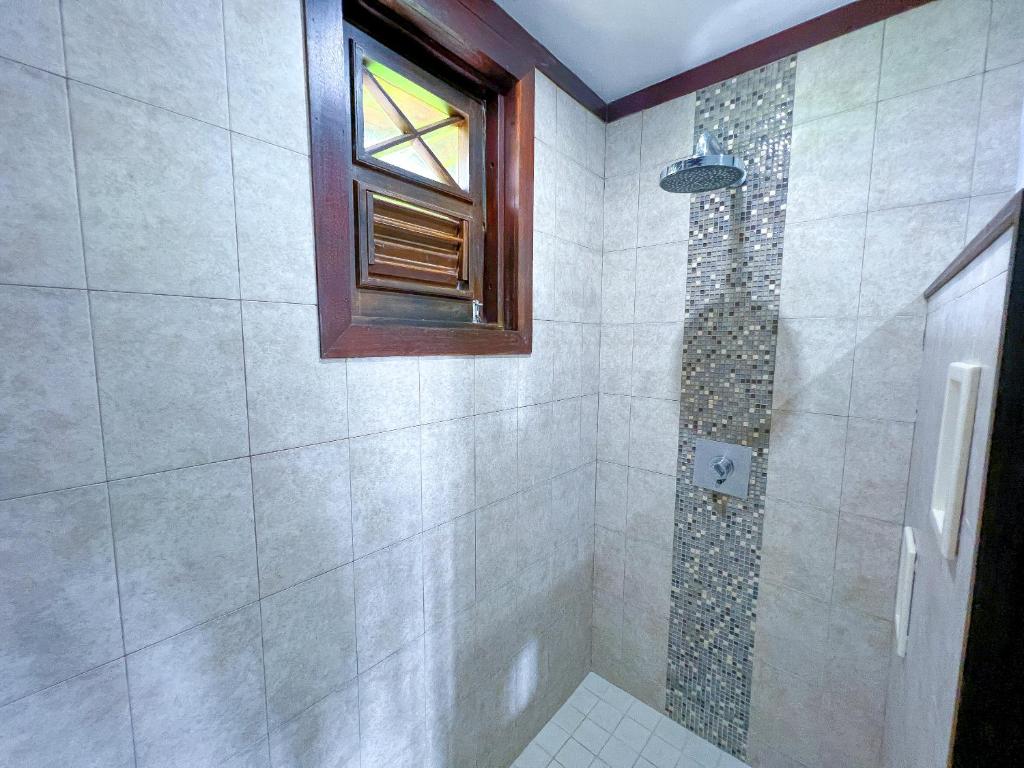 a bathroom with a shower with a window at Santosha Barbados in Saint Andrew