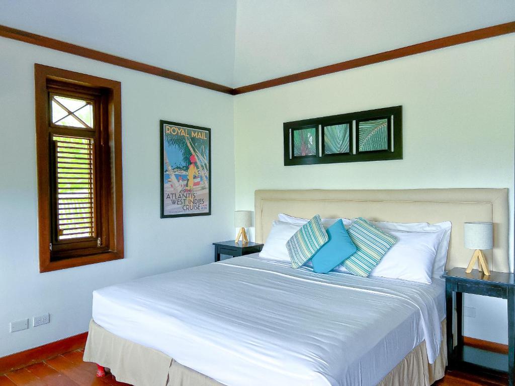 a bedroom with a large white bed with blue pillows at Santosha Barbados in Saint Andrew