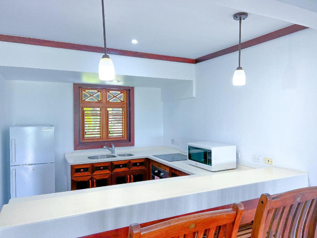 a kitchen with a white counter and a microwave at Santosha Barbados in Saint Andrew
