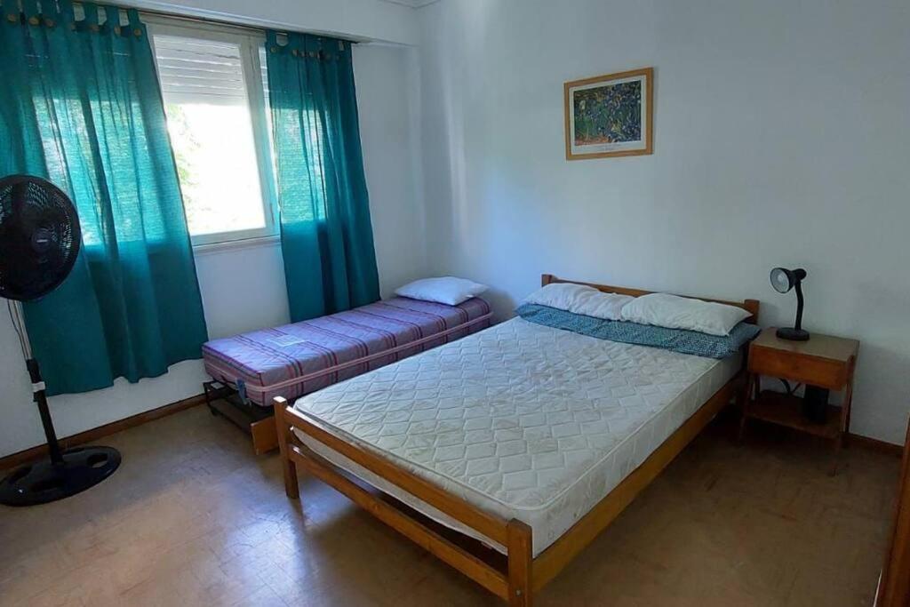 1 dormitorio con 2 camas y una ventana con cortinas verdes en Depto mardel cómodo luminoso cerca de todo en Mar del Plata