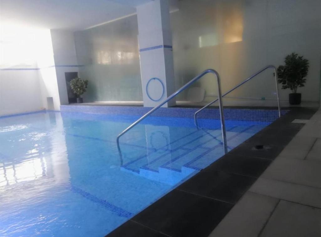 a swimming pool with blue water and stairs in a building at The Pearl in Yehud
