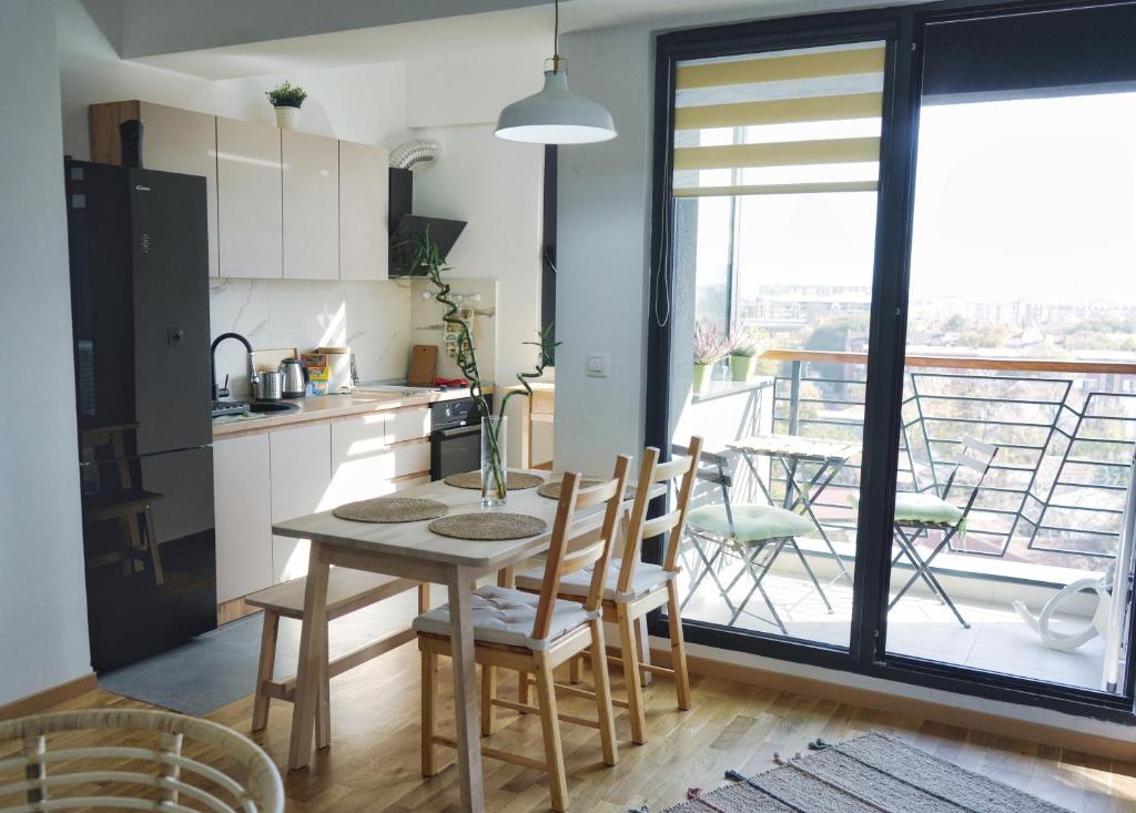 a kitchen with a table and chairs and a balcony at Sunlight Apartment in Skopje