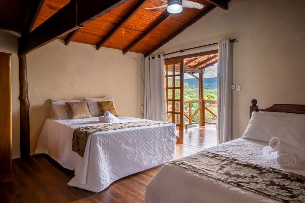 a bedroom with two beds and a sliding glass door at LUAR DO MIRANTE ,casa com AR p temporada piscina aquecida hidro dentro da cidade in Pirenópolis