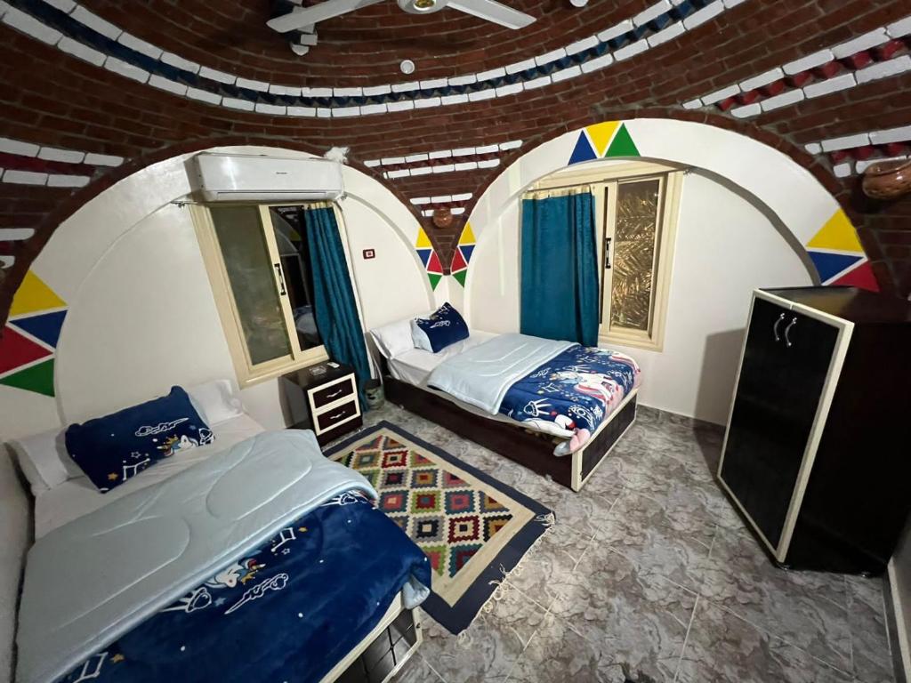 Habitación con 2 camas y 2 ventanas. en Noura hasel nubian house en Asuán