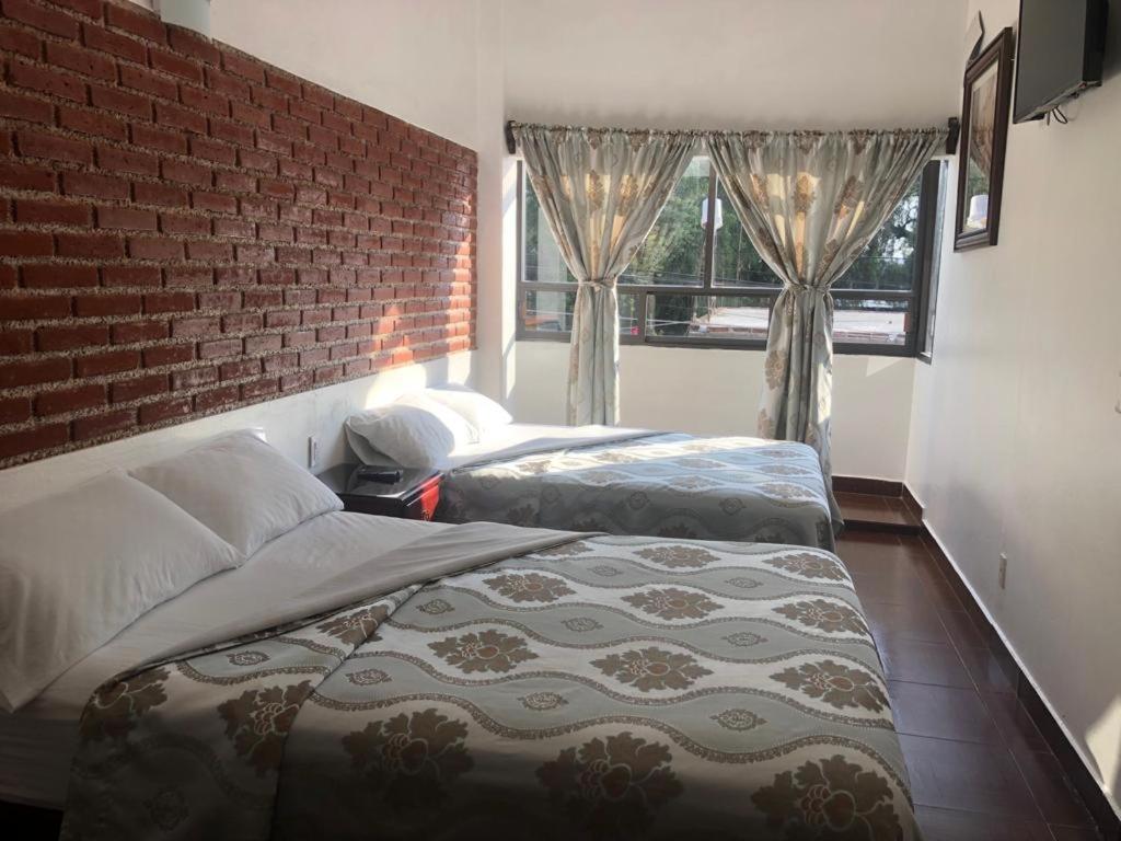 Hotel CALLI YOLOTL Teotihuacan في سان جان تيوتيهواكان: غرفة نوم بسريرين وجدار من الطوب