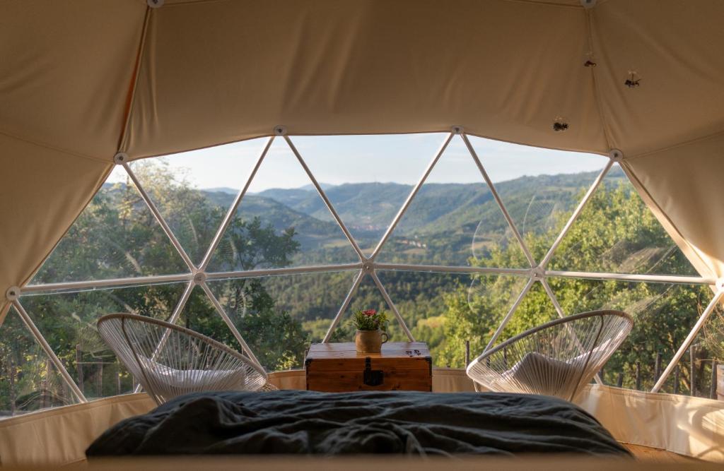 a bed and two chairs in a room with a large window at Gaia’s Spheres in Gorzegno