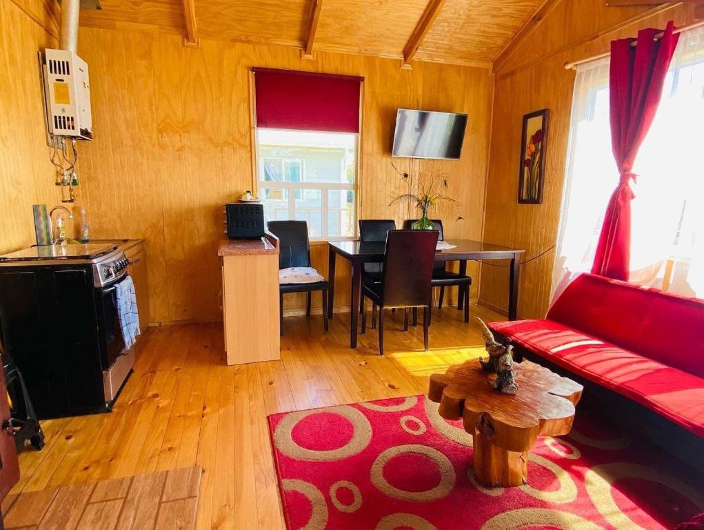 sala de estar con sofá rojo y mesa en Cabañas Agroturismo Pupelde, en Ancud