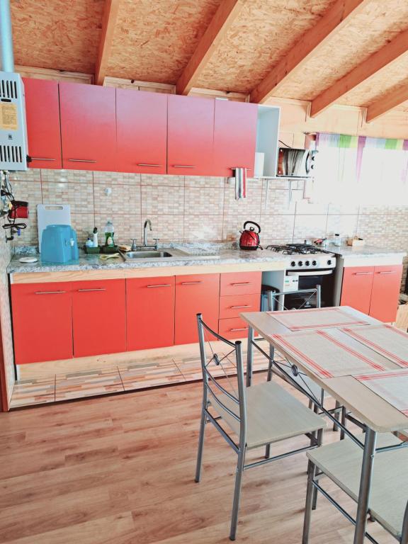 uma cozinha com armários vermelhos e uma mesa com cadeiras em Cabañas Tripanko Chiloe em Ancud