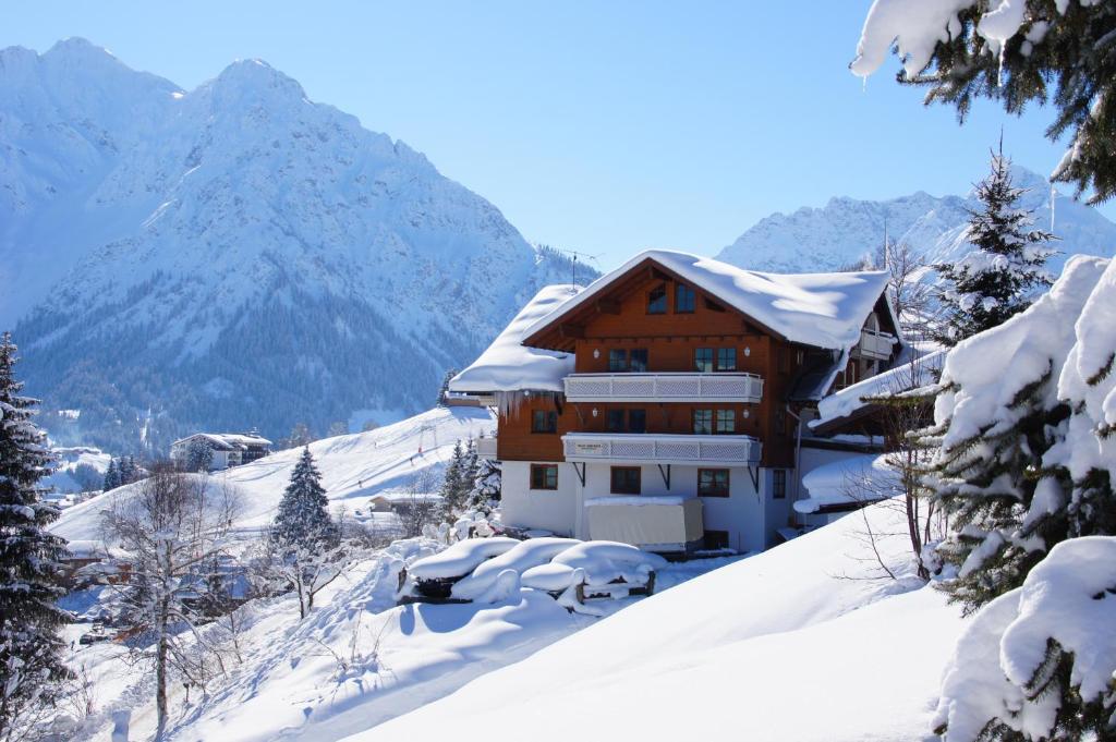 una casa en la nieve con montañas en el fondo en Gästehaus am Berg, en Hirschegg