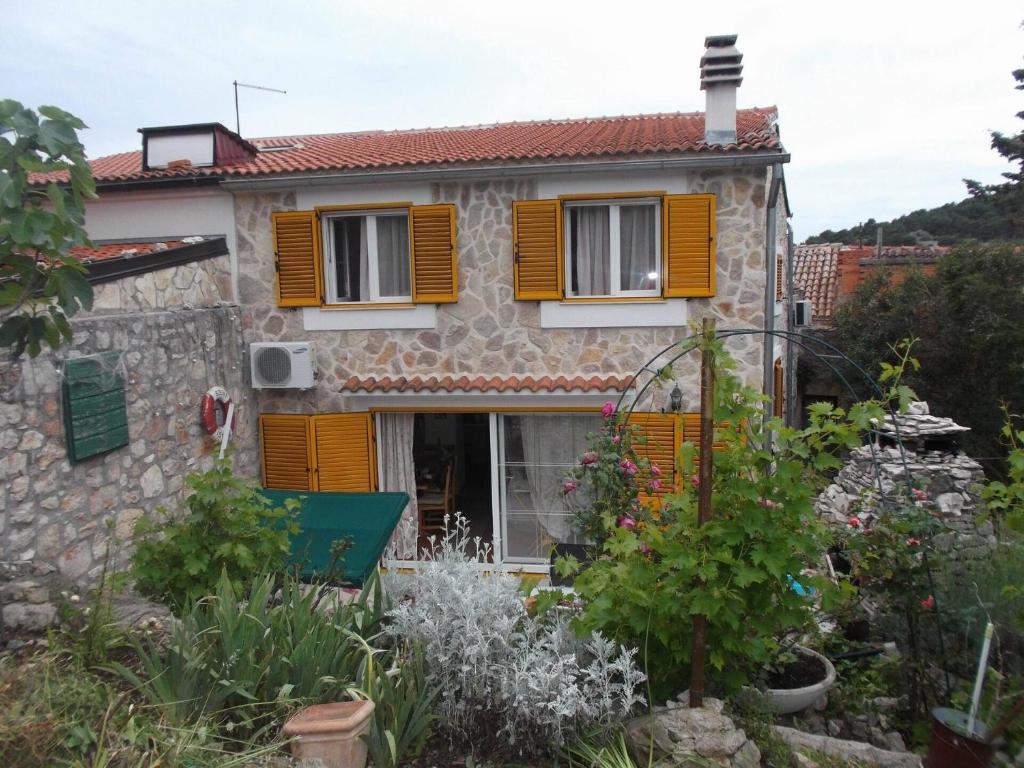 Casa con persianas amarillas y jardín en Apartments Sunce, en Murter