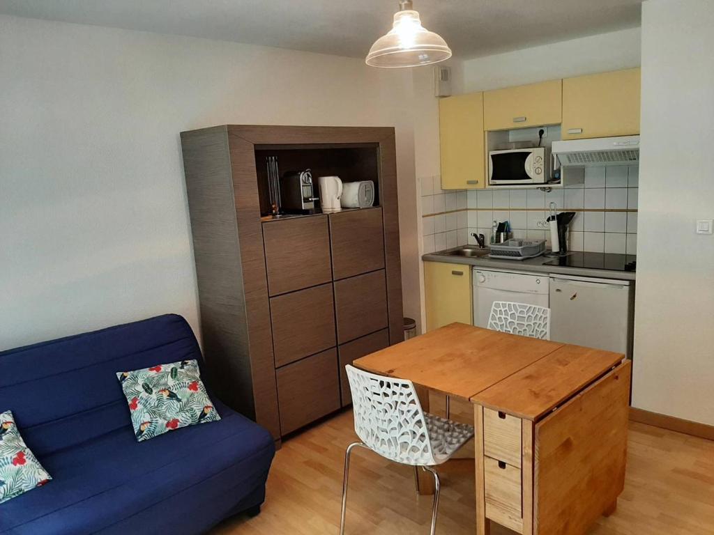 un salon avec un canapé bleu et une cuisine dans l'établissement Appartement cosy pour 4-6 pers, proche centre, parking, casier à ski, Cauterets - FR-1-234-294, à Cauterets