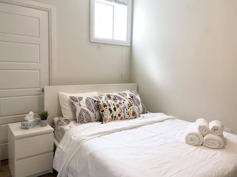 Un dormitorio con una cama blanca con toallas. en Beautiful Walk out Basement Apartment in Pickering near Beach en Pickering