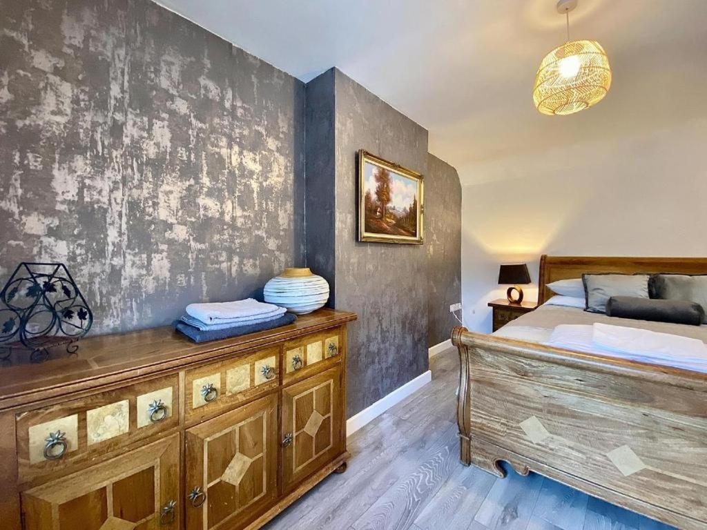 um quarto com uma cama e uma cómoda em madeira em House 1905 - Self Catering Serviced Apartment em North Tidworth