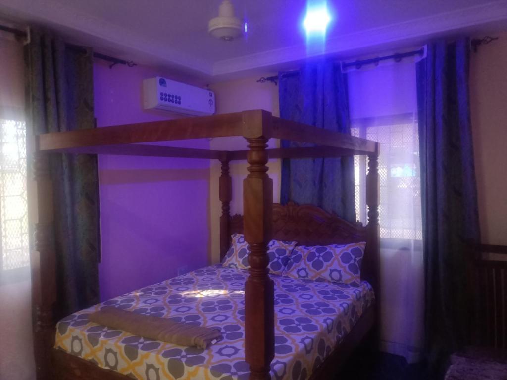 Dormitorio con cama con dosel en habitación púrpura en Coasterian Apartment, en Mombasa