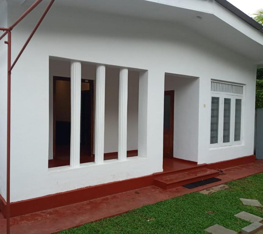 ein Bild eines Hauses mit weißen Wänden und grünem Gras in der Unterkunft Villa Arunodaya in Hikkaduwa