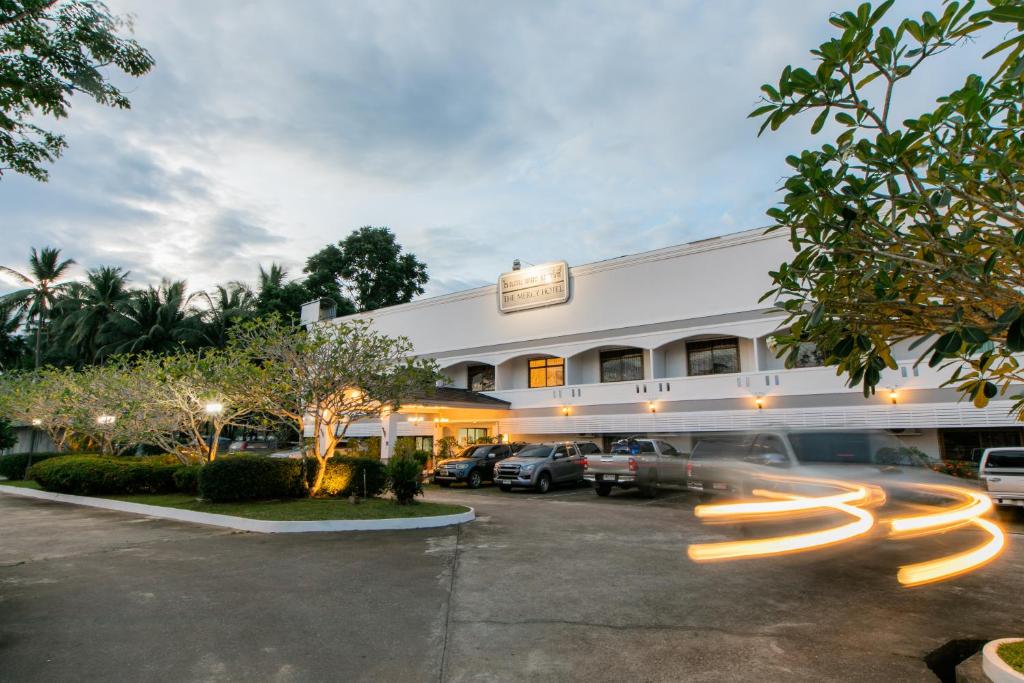 a building with cars parked in a parking lot at The Mercy Hotel in Chumphon