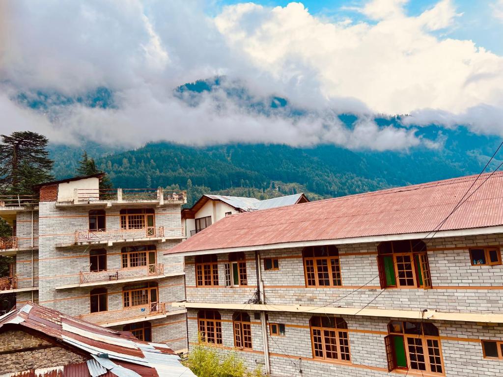 a building with a red roof in front of a mountain at Hotel Solitaire Manali - A Few Steps From Mall Road in Manāli