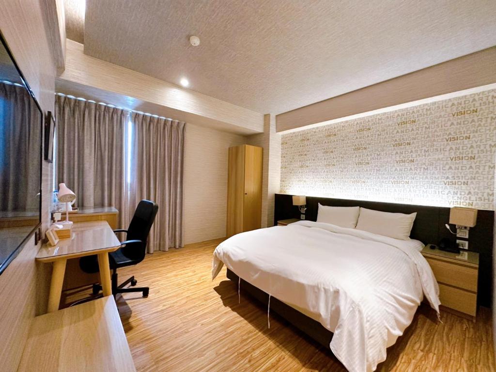 a hotel room with a bed and a desk and a television at DLInn Hotel in Taichung