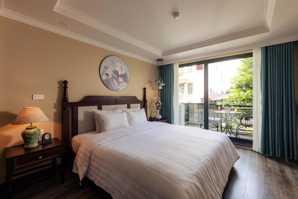um quarto com uma cama grande e uma varanda em Lotusama Hanoi Hotel em Hanói