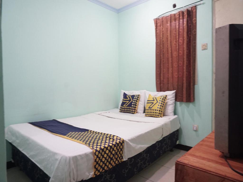 ein Schlafzimmer mit einem Bett mit Kissen und einem TV in der Unterkunft SPOT ON 91860 Amazon Homestay Syariah 2 in Sukabumi