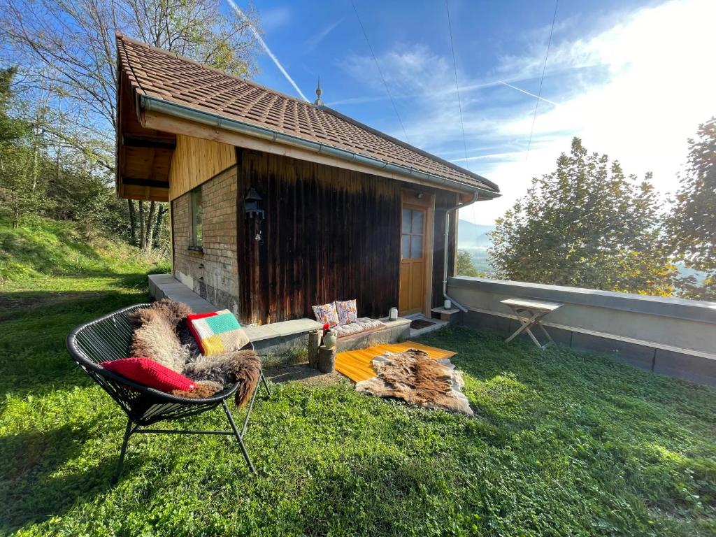 uma pequena cabana com uma cadeira em frente em Jolie cabane avec jacuzzi pour les amoureux de la nature em Tullins