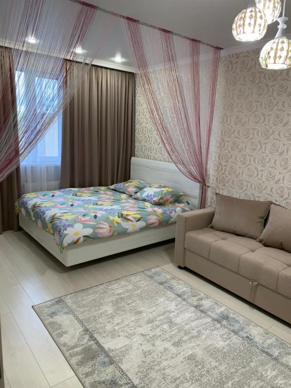 1 dormitorio con 1 cama y 1 sofá en 1 комнатная квартира, en Astana