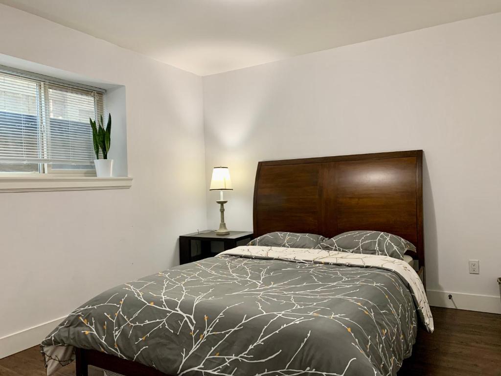 a bedroom with a bed with a wooden headboard and a window at Spacious Burnaby Guest Home in Burnaby