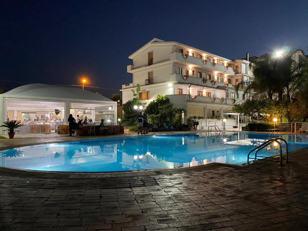 a swimming pool in front of a building at night at Hotel Il Corsaro in Le Castella