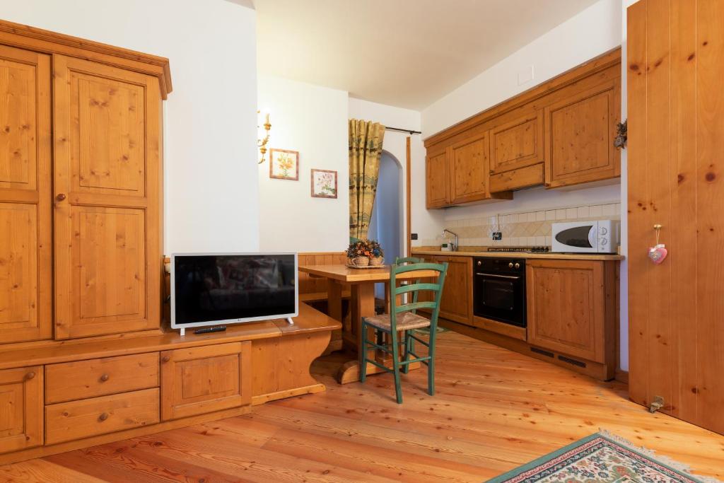 a kitchen with wooden cabinets and a table with a television at Patrioti 51 - Asiago Centro in Asiago