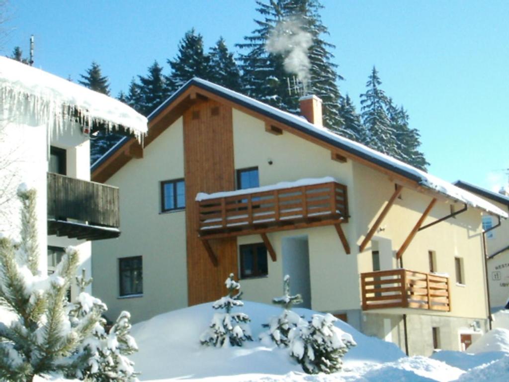 a house with a balcony in the snow at Pension Lenka 1 in Harrachov