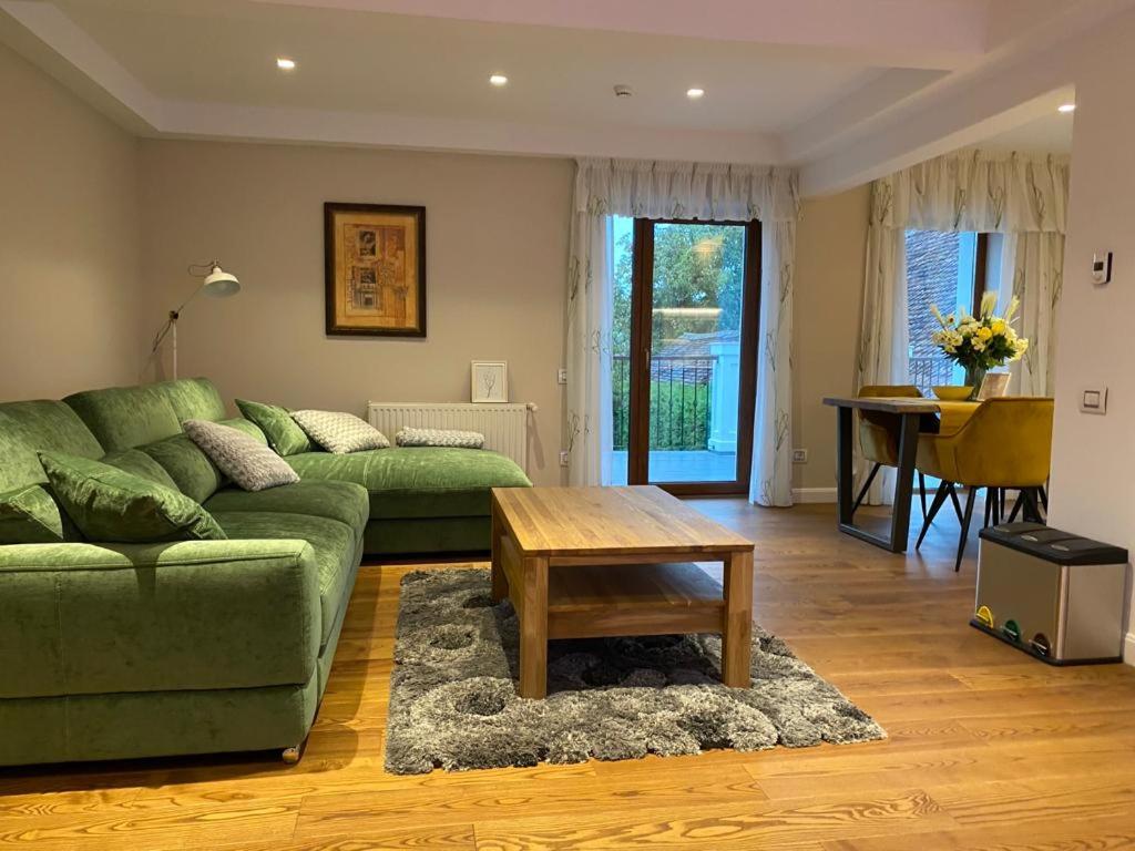 sala de estar con sofá verde y mesa en ApartamentS en Rîşnov