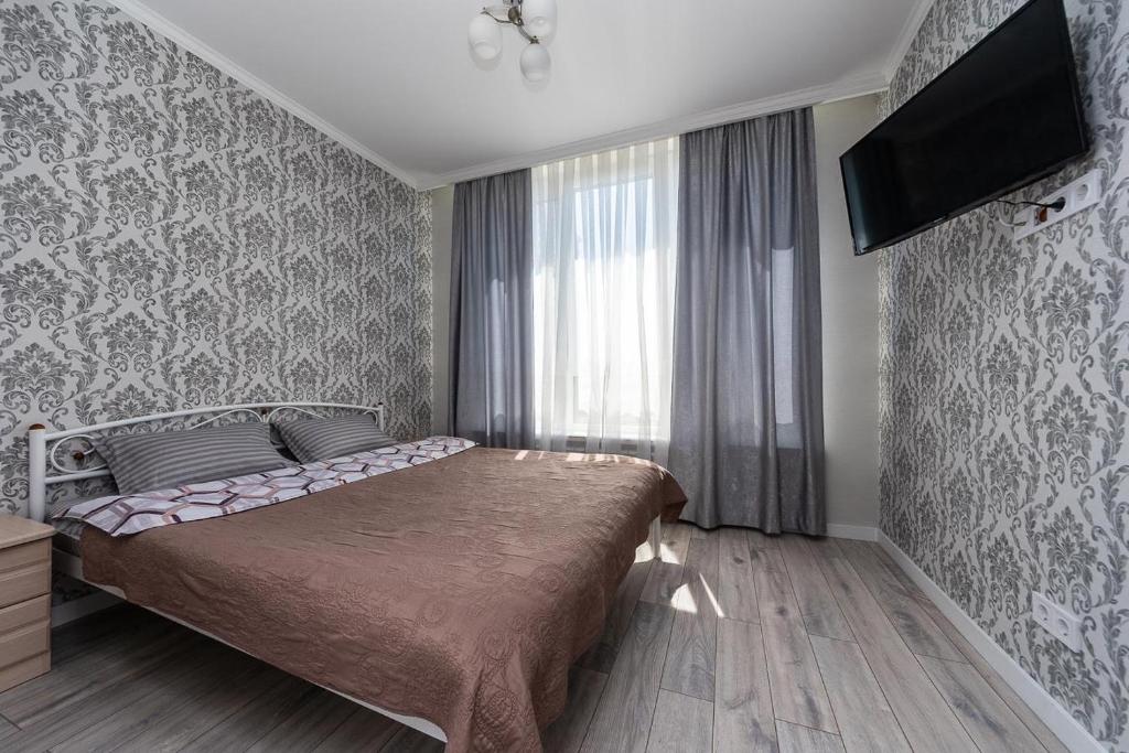 ein Schlafzimmer mit einem Bett und einem TV an der Wand in der Unterkunft Апартаменты метро Вырлица in Kiew