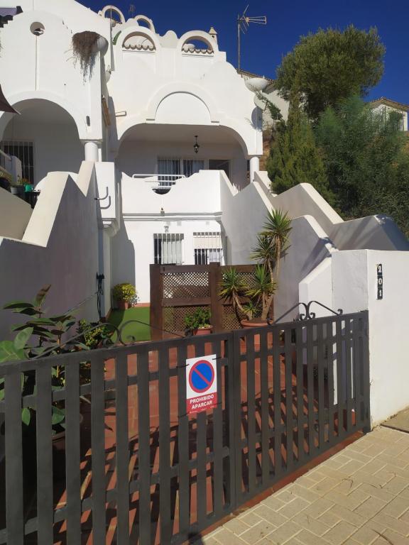 una casa blanca con un cartel en una valla en Casa adosada La Reserva de Marbella, en Marbella