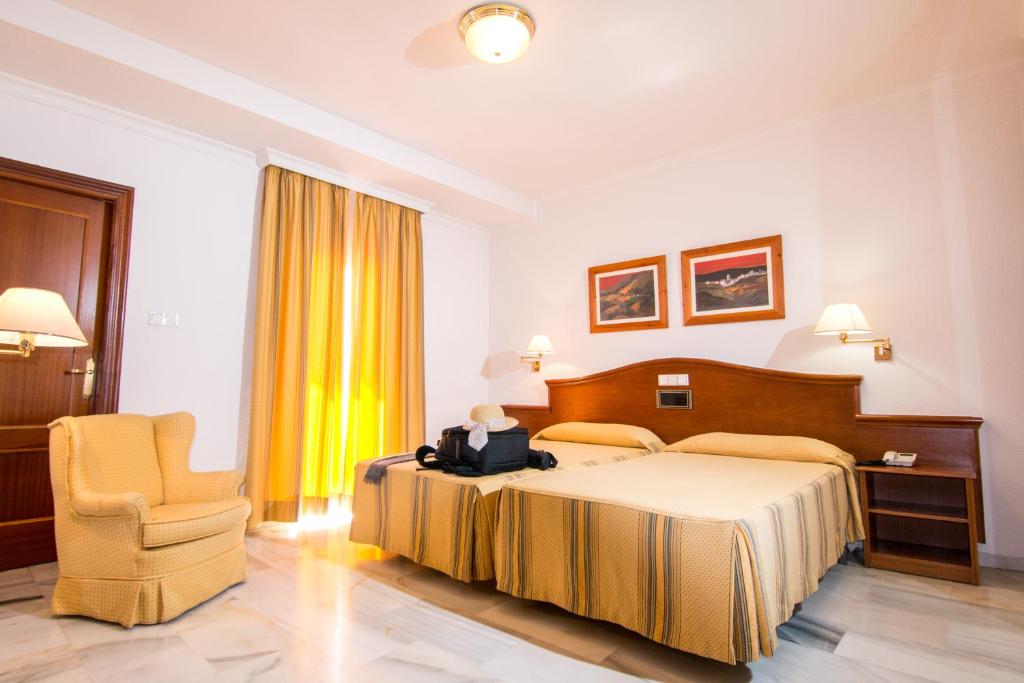 ロハにあるHotel Abades Lojaのベッドと椅子付きのホテルルーム