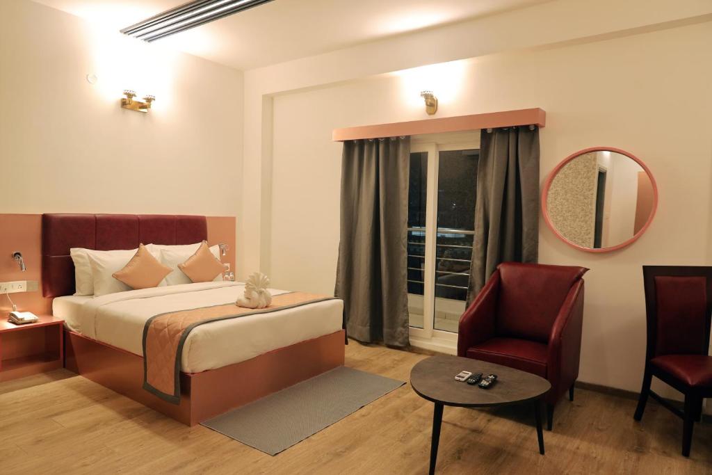 a bedroom with a bed and a chair and a mirror at RV STAY INN in Yelahanka