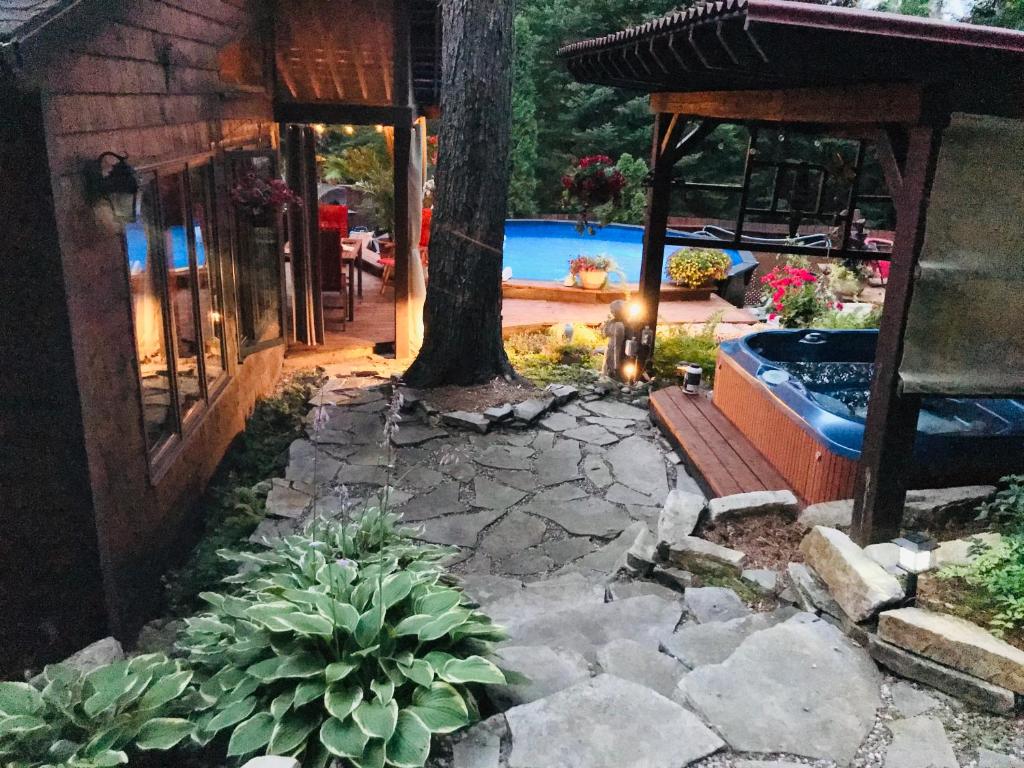 a backyard with a tree and a swimming pool at PETIT COIN DE PARADIS in Sainte Anne des Lacs