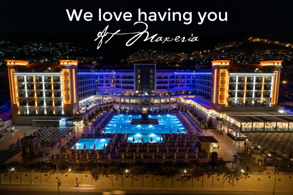 una vista de un hotel por la noche con las palabras que nos encanta tenerte fuera de los bailarines en Maxeria Blue Didyma en Didim