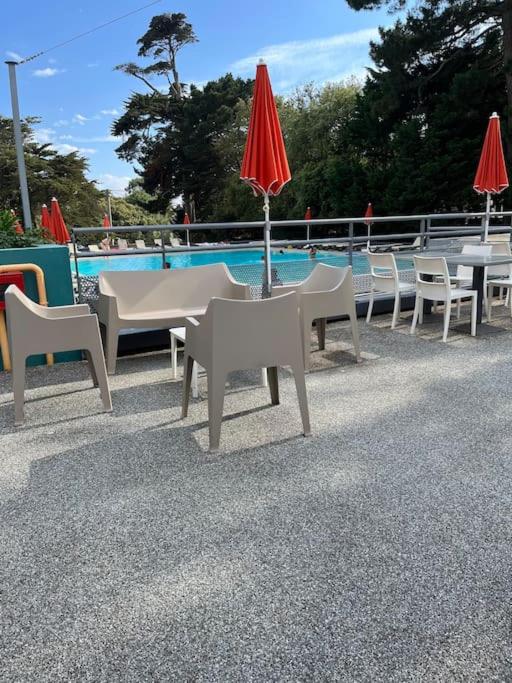 - un groupe de tables et de chaises avec parasols à côté d'une piscine dans l'établissement Agréable appartement dans Résidence à Pornichet, à Pornichet