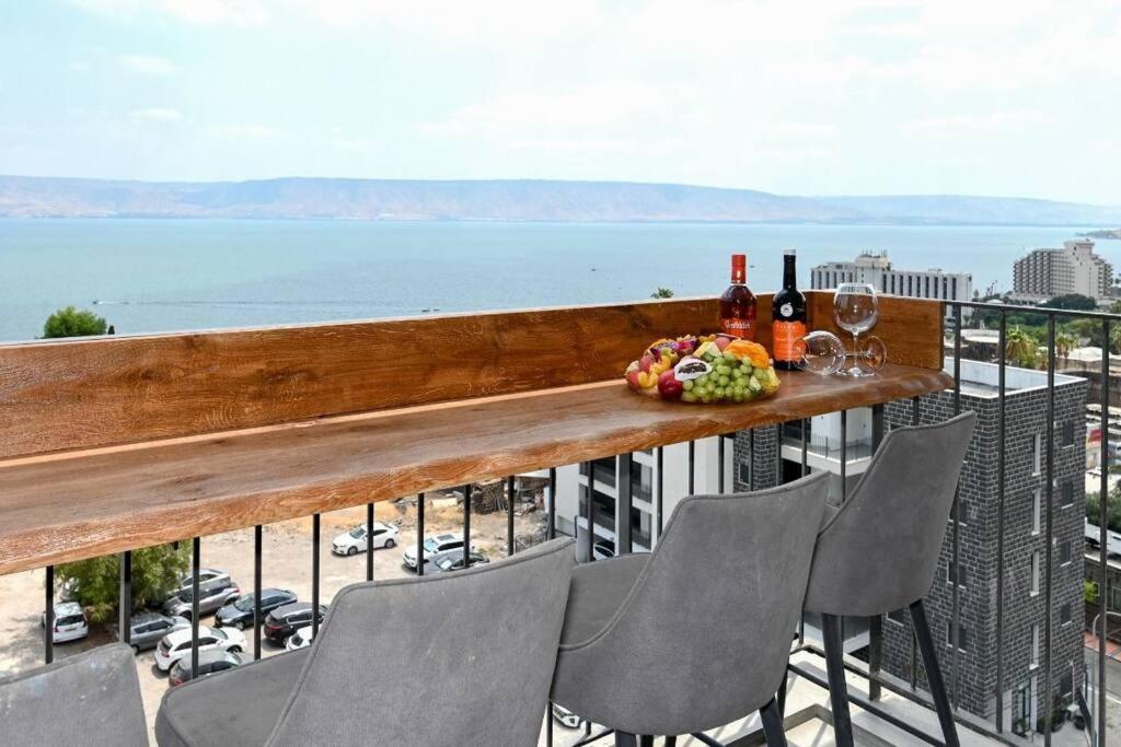 una mesa con sillas y botellas de vino en el balcón en L.T.D- MY VIEW. 2 bedroom apartment by the lake. en Tiberias