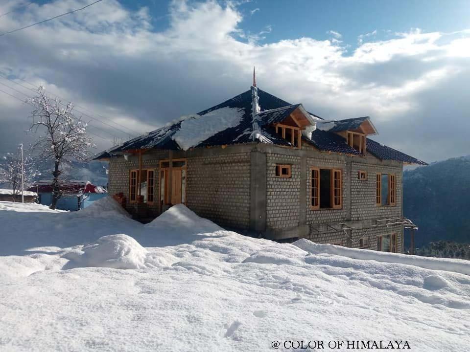 uma casa no topo de uma montanha coberta de neve em Loghouse at khajjiar lake em Khajjiar 